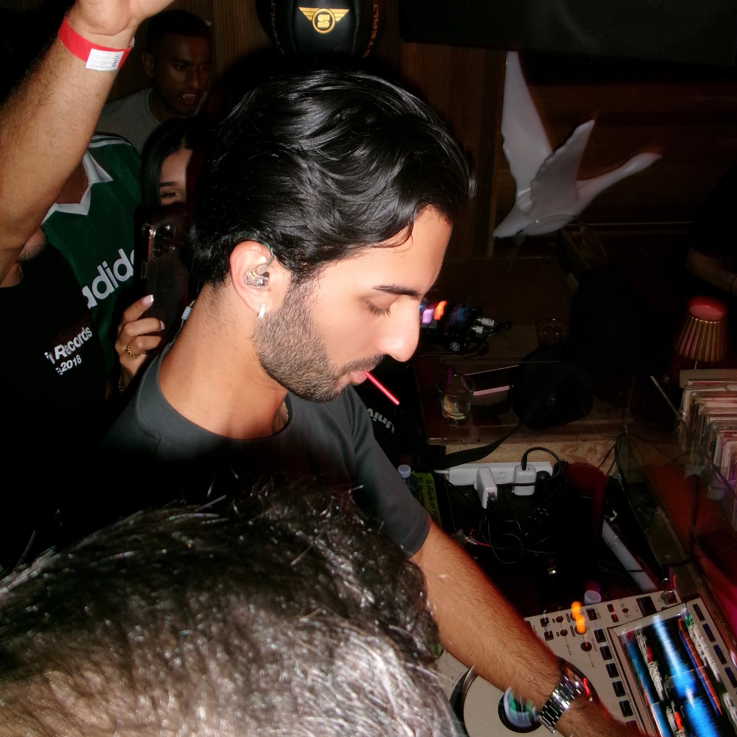 Person at a DJ booth with equipment and a dark background