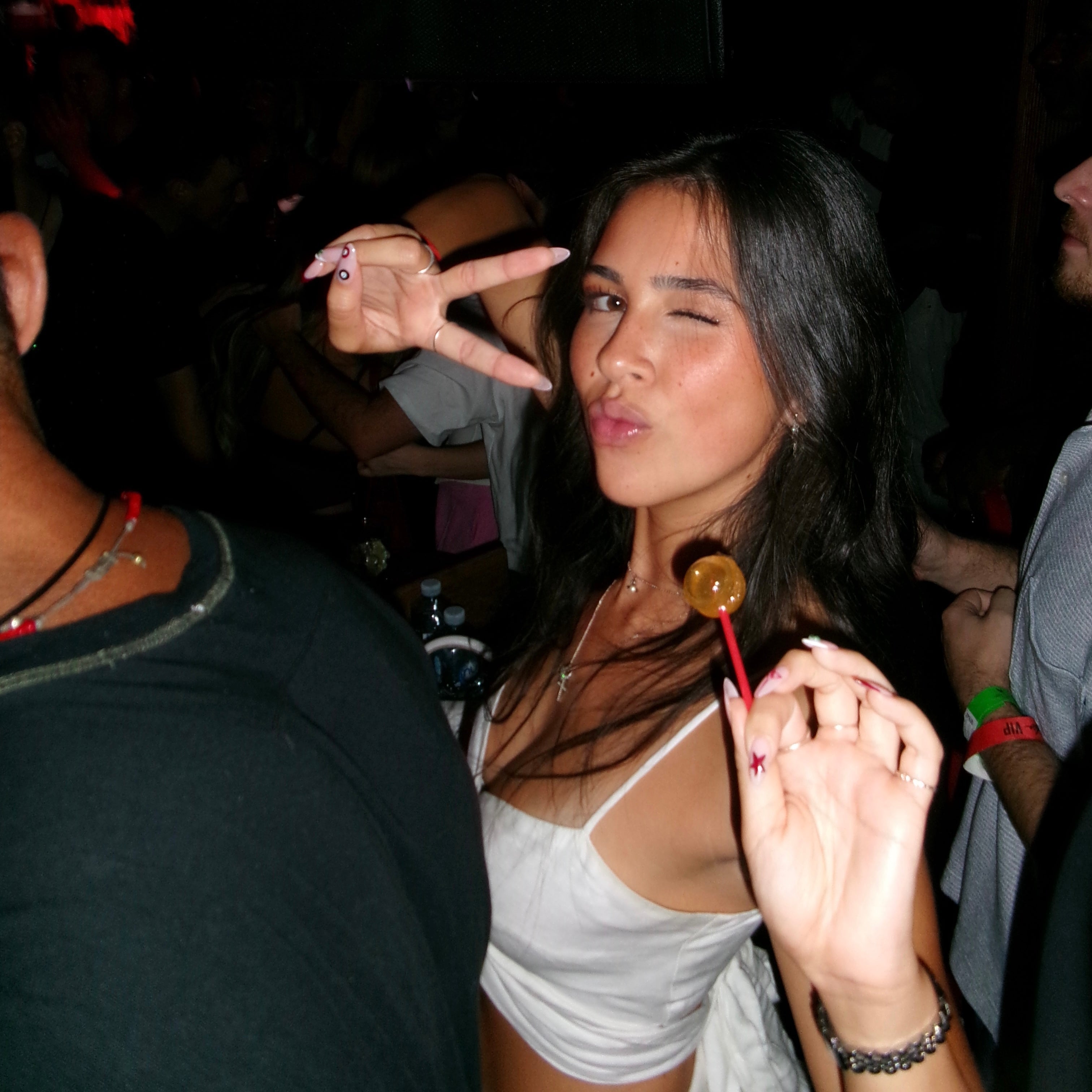 Woman making a peace sign with her hand at a party.